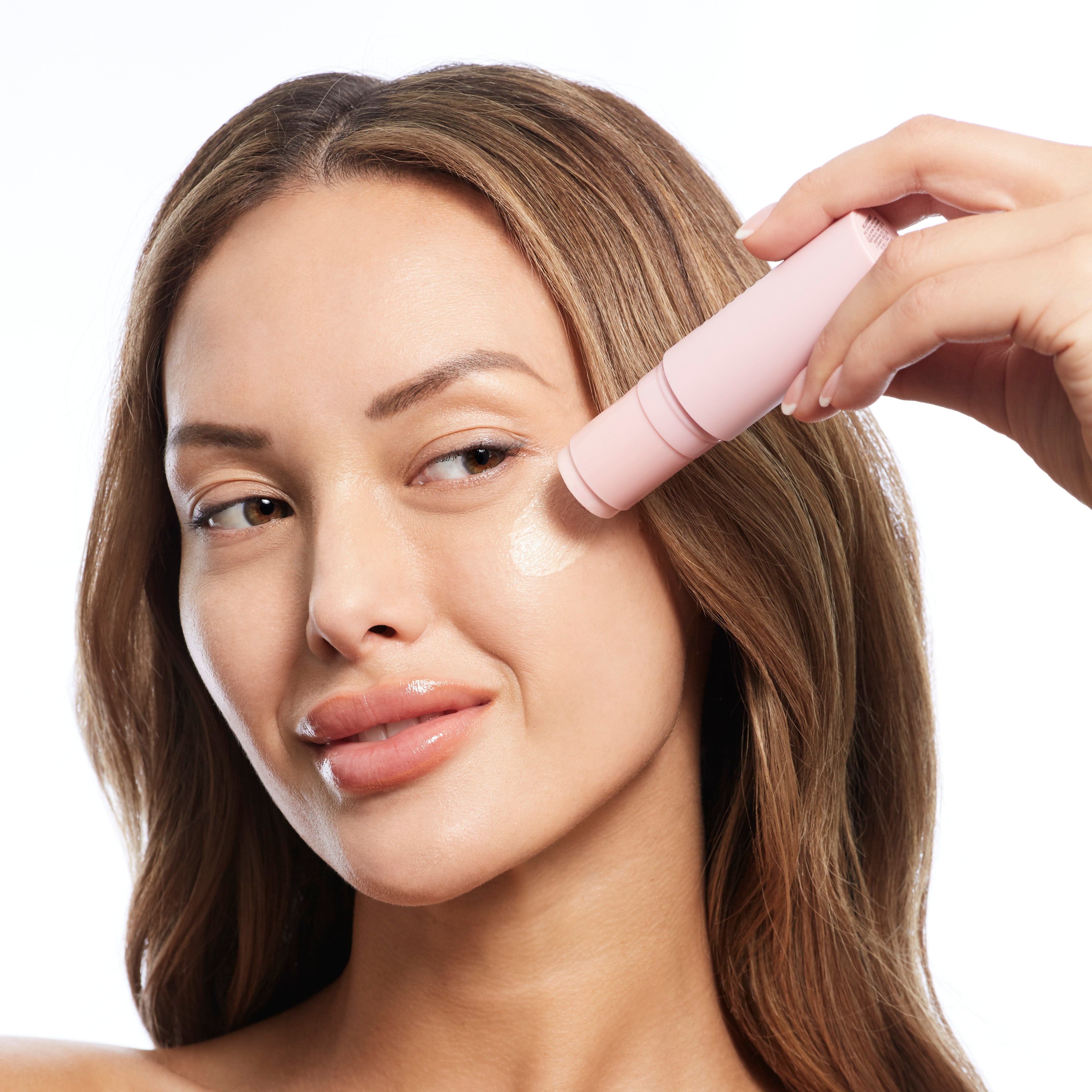Woman applying makeup stick to her cheek