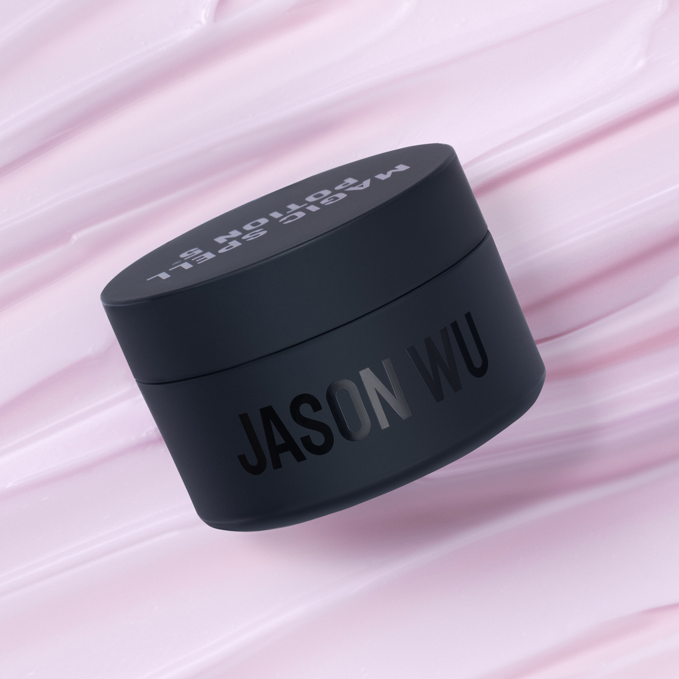 Black cosmetic jar with 'Jason Wu' label on a pink textured background.