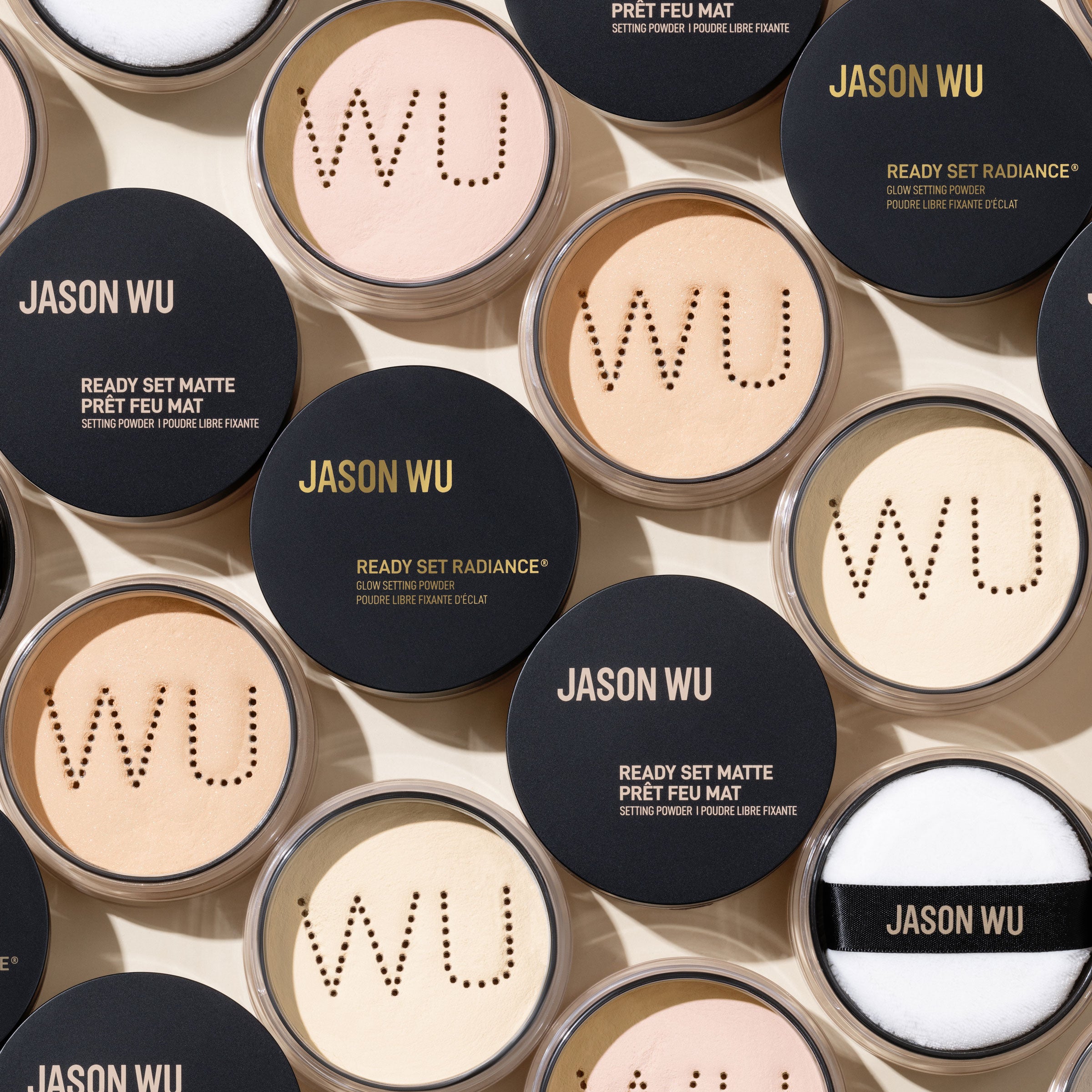 Various shades of makeup powders with black and transparent lids labeled 'Jason Wu'.