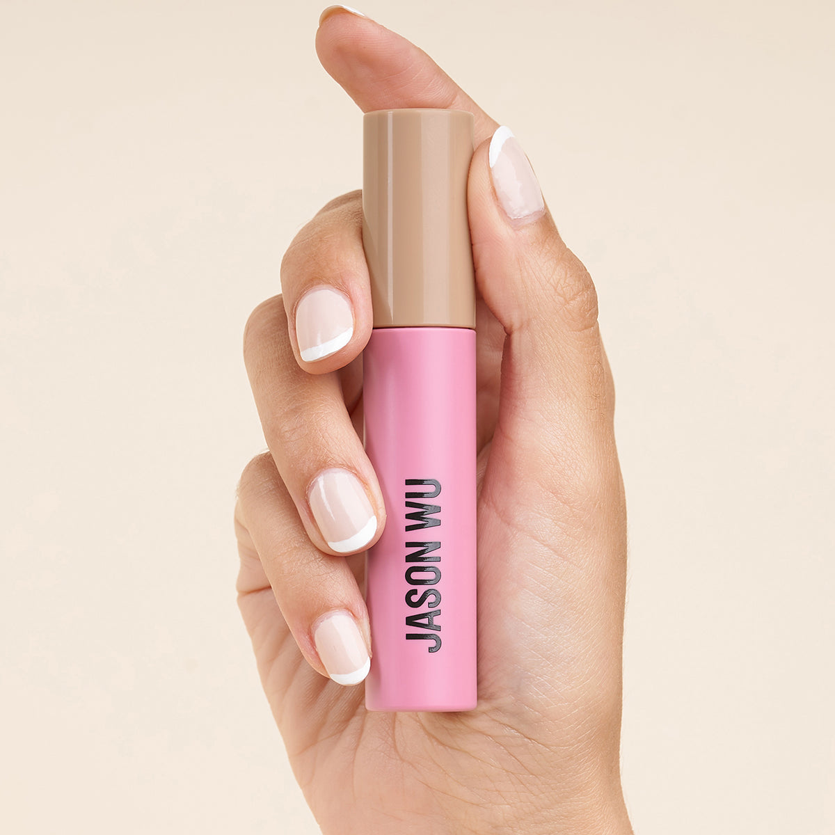 Hand holding a pink cosmetic product labeled Jason Wu