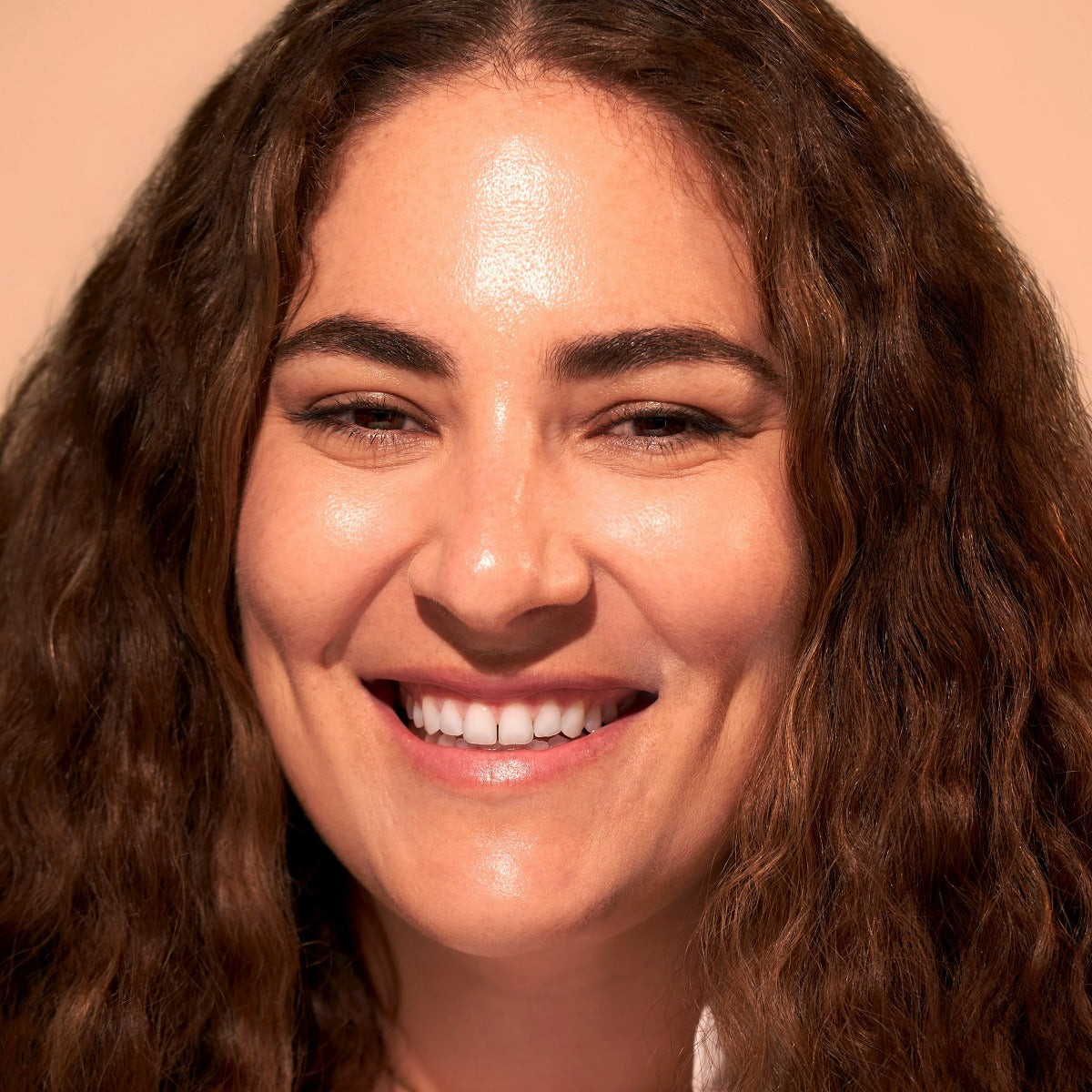 Person with curly brown hair smiling.