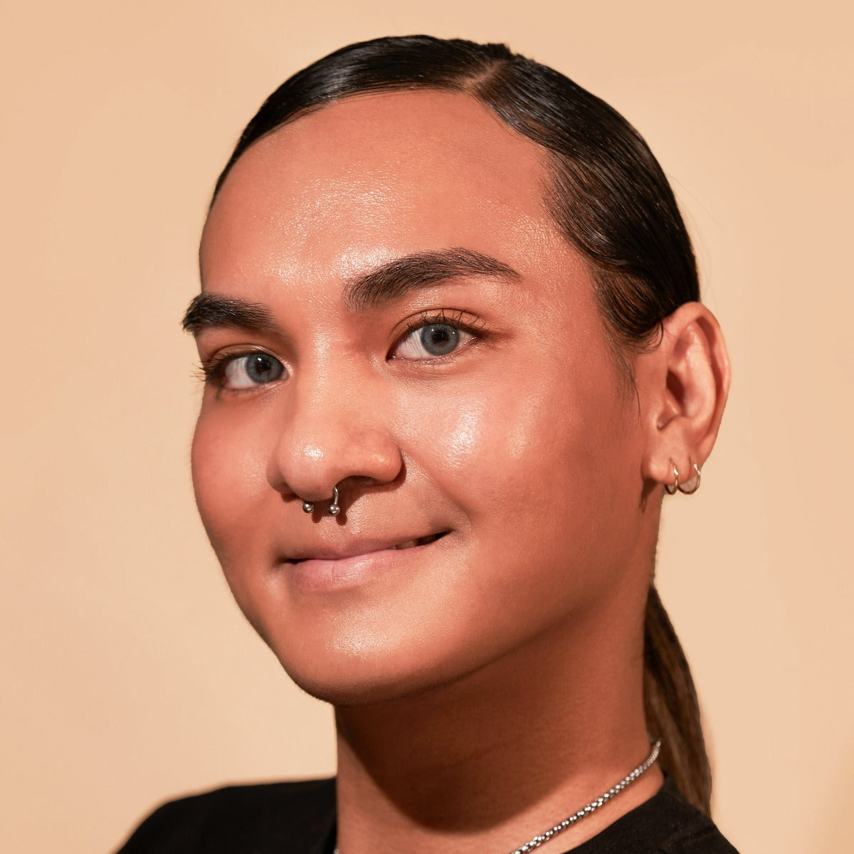 Smiling person with a nose ring and earrings