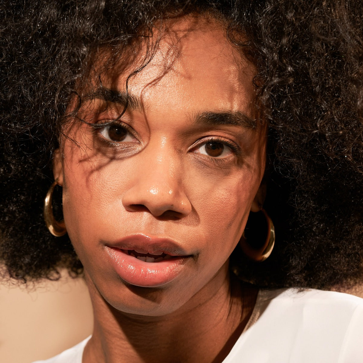 Close-up portrait of a person with curly hair and hoop earrings.