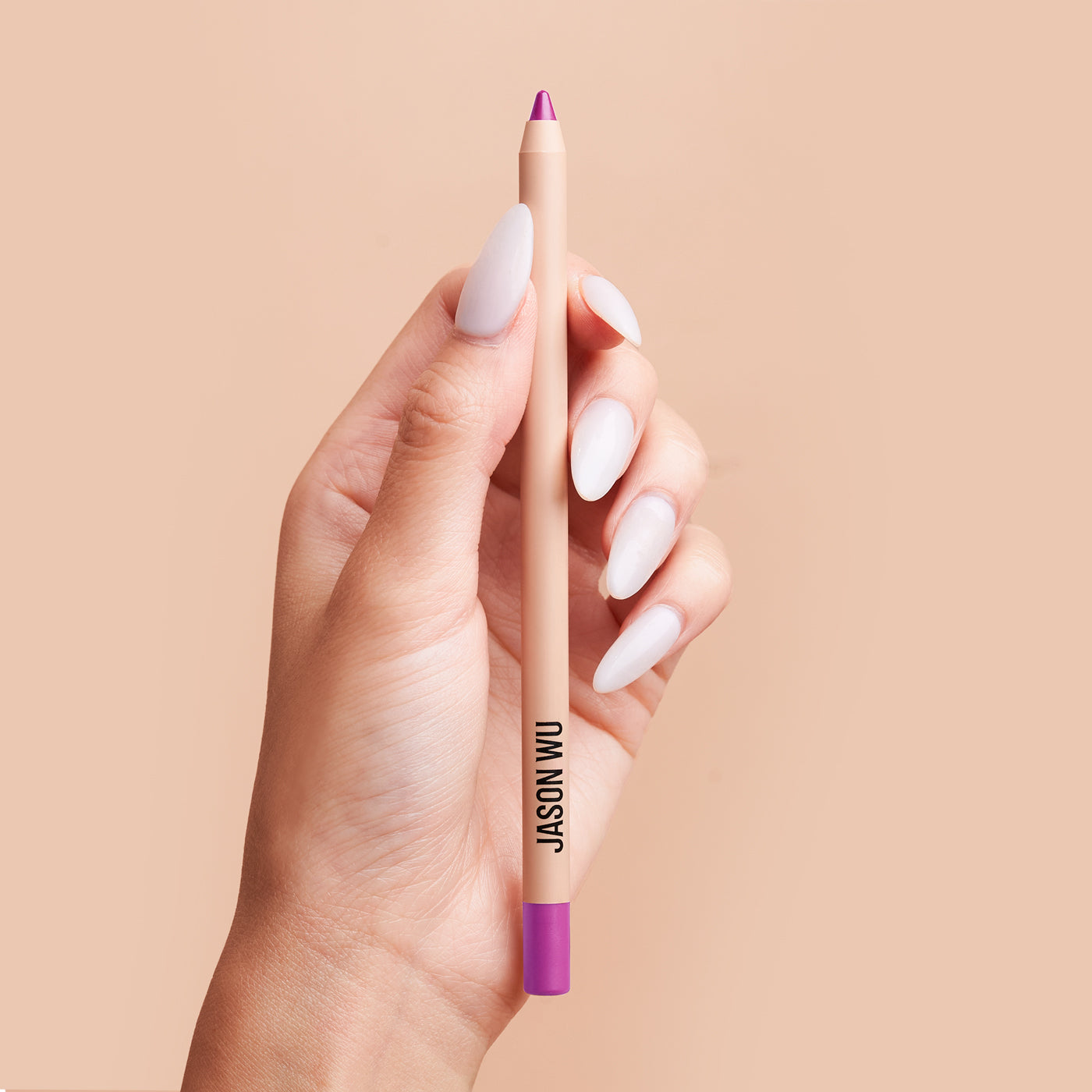 Hand holding a pink lip liner pencil against a neutral background.