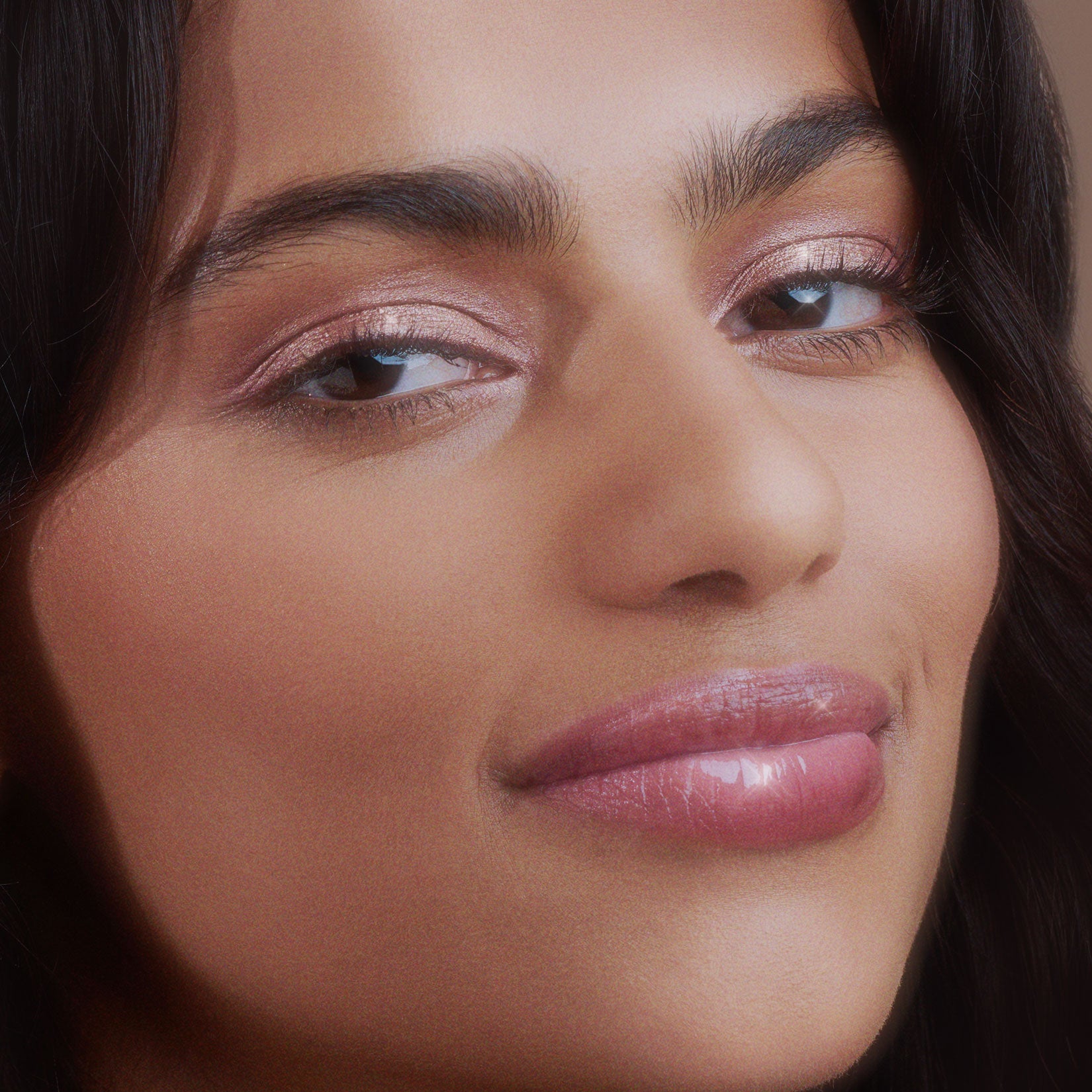 Close-up of a person with shiny pink lipstick and glittery eye makeup.