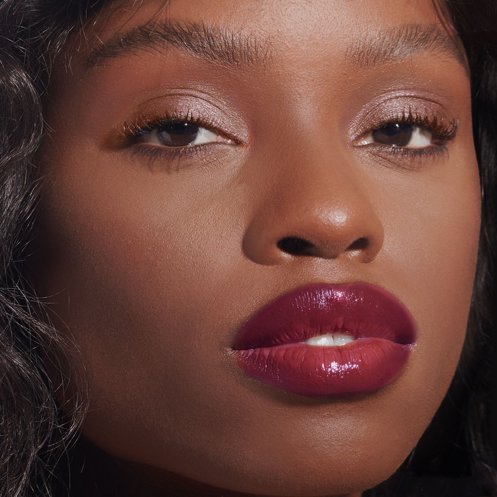 Close-up of a person with glossy lips and long eyelashes.