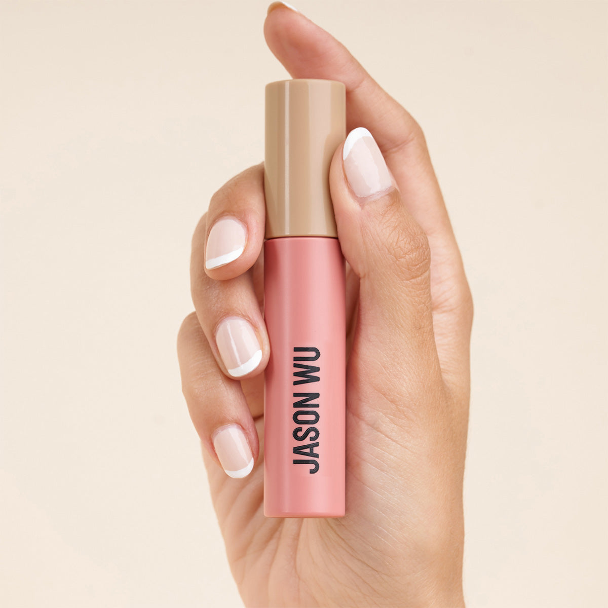 Hand holding a pink makeup product with 'Jason Wu' label.