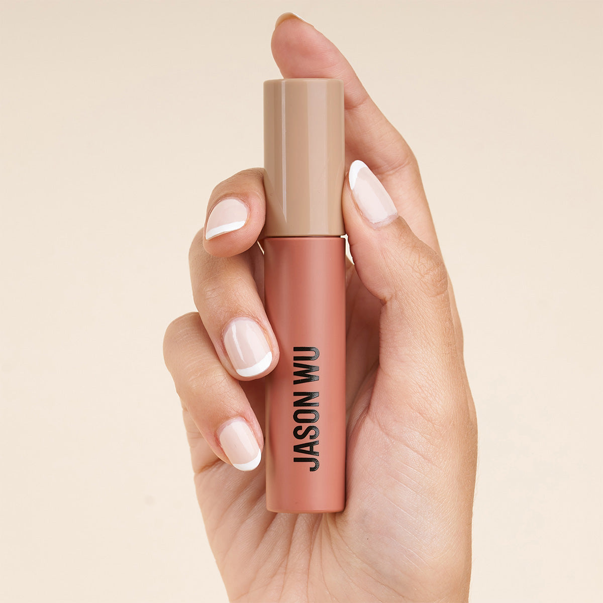 Hand holding a cosmetic product with 'Jason Wu' label