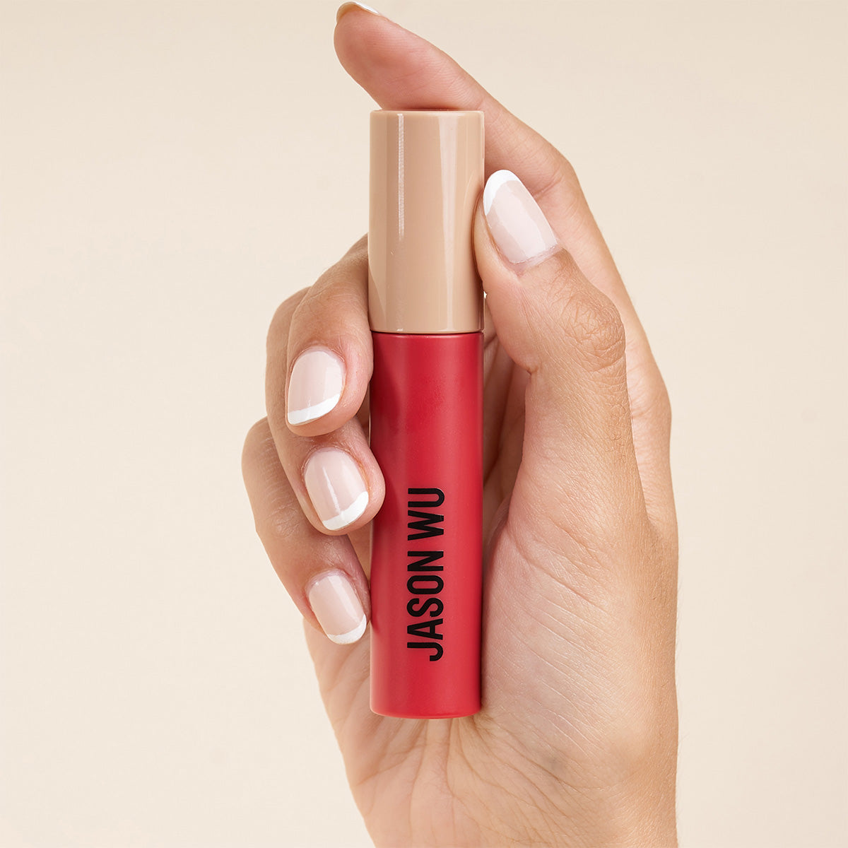 Hand holding a red and beige lipstick tube