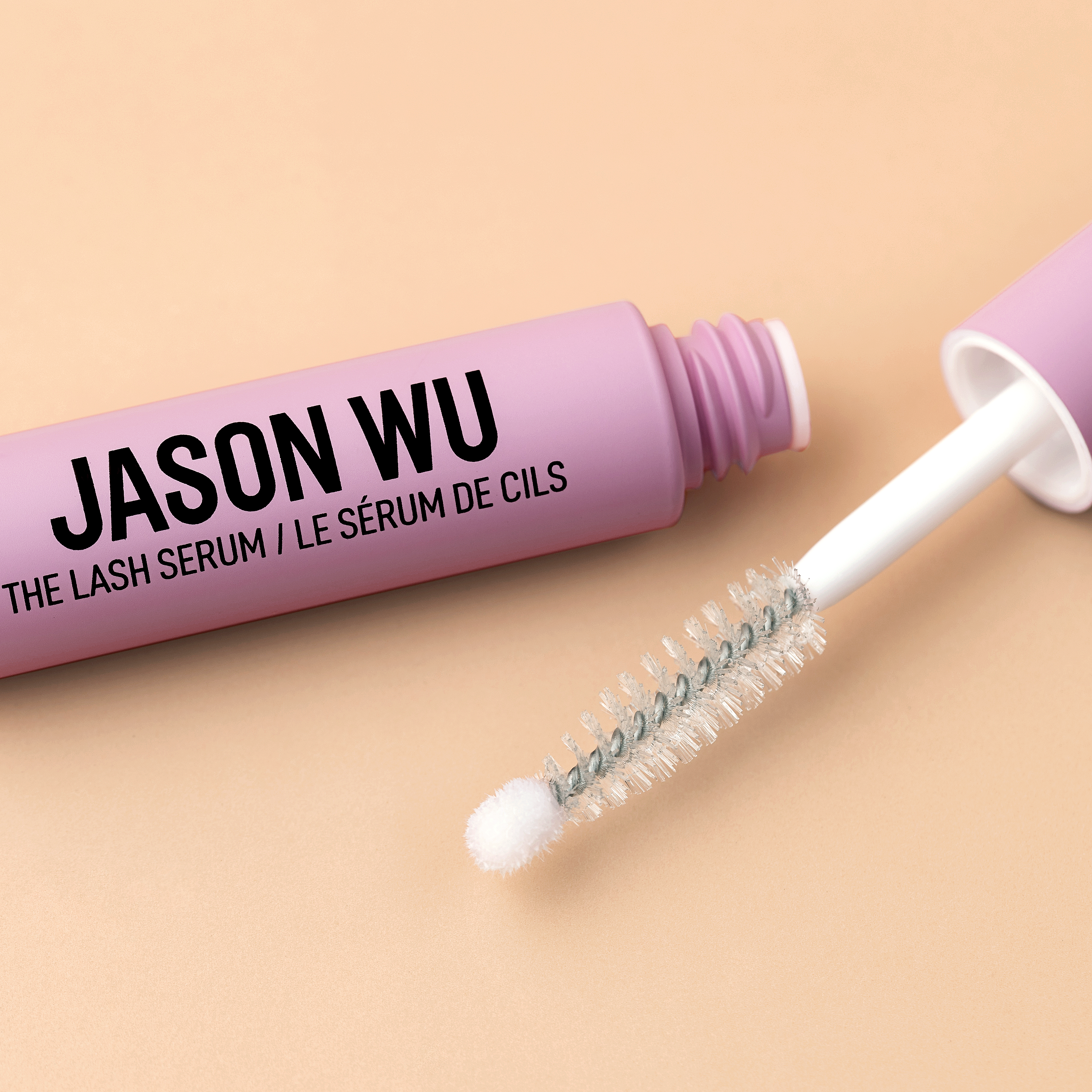 Close-up of Jason Wu lash serum on a peach background.